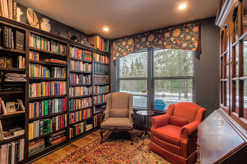 Imagen de sala de estar con biblioteca tradicional con paredes grises, suelo de madera en tonos medios y suelo marrón