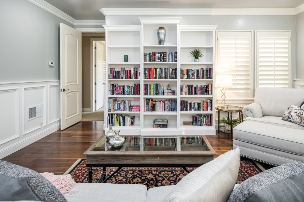 Foto di un grande soggiorno classico chiuso con libreria, pareti bianche, pavimento in legno massello medio, nessun camino, nessuna TV e pavimento marrone