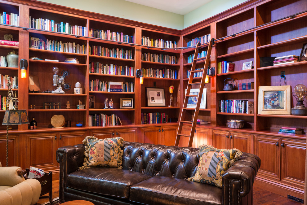 Immagine di un grande soggiorno chic aperto con libreria, pareti beige, parquet scuro, camino classico, nessuna TV, pavimento marrone e cornice del camino in intonaco