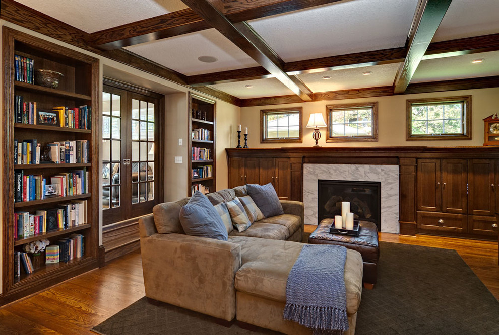 Ejemplo de sala de estar con biblioteca cerrada tradicional de tamaño medio con paredes beige, suelo de madera en tonos medios, todas las chimeneas y marco de chimenea de baldosas y/o azulejos