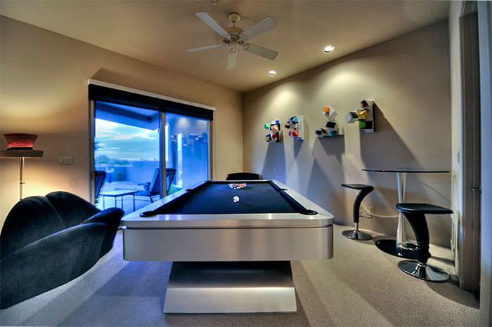 Expansive retro open plan games room in Phoenix with a game room, beige walls, travertine flooring, a standard fireplace, a stone fireplace surround and no tv.