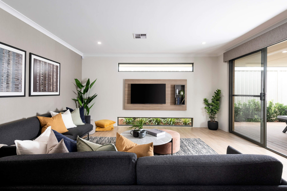 На фото: гостиная комната в современном стиле с бежевыми стенами, светлым паркетным полом, телевизором на стене и бежевым полом