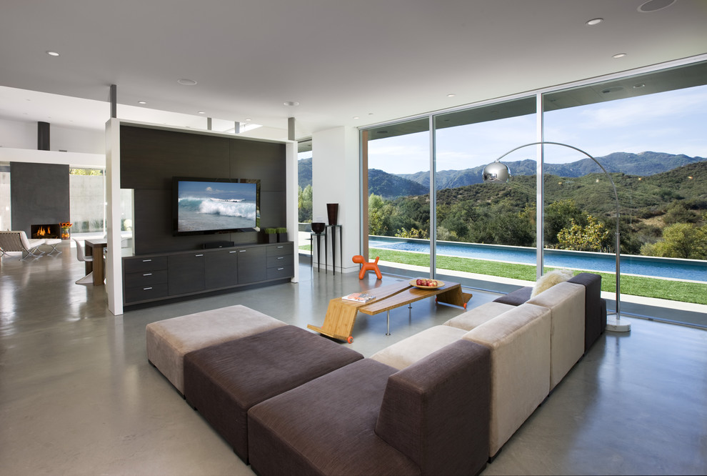 На фото: большая гостиная комната в современном стиле с бетонным полом, белыми стенами, угловым камином, фасадом камина из металла и телевизором на стене