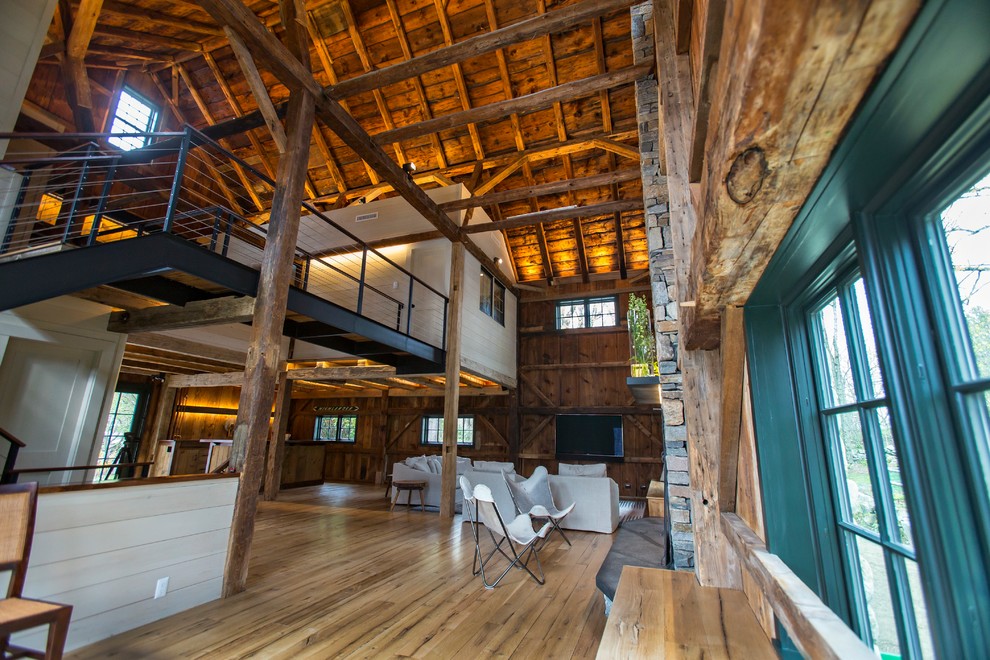Diseño de sala de estar abierta rural grande con suelo de madera clara, todas las chimeneas, marco de chimenea de piedra y suelo beige
