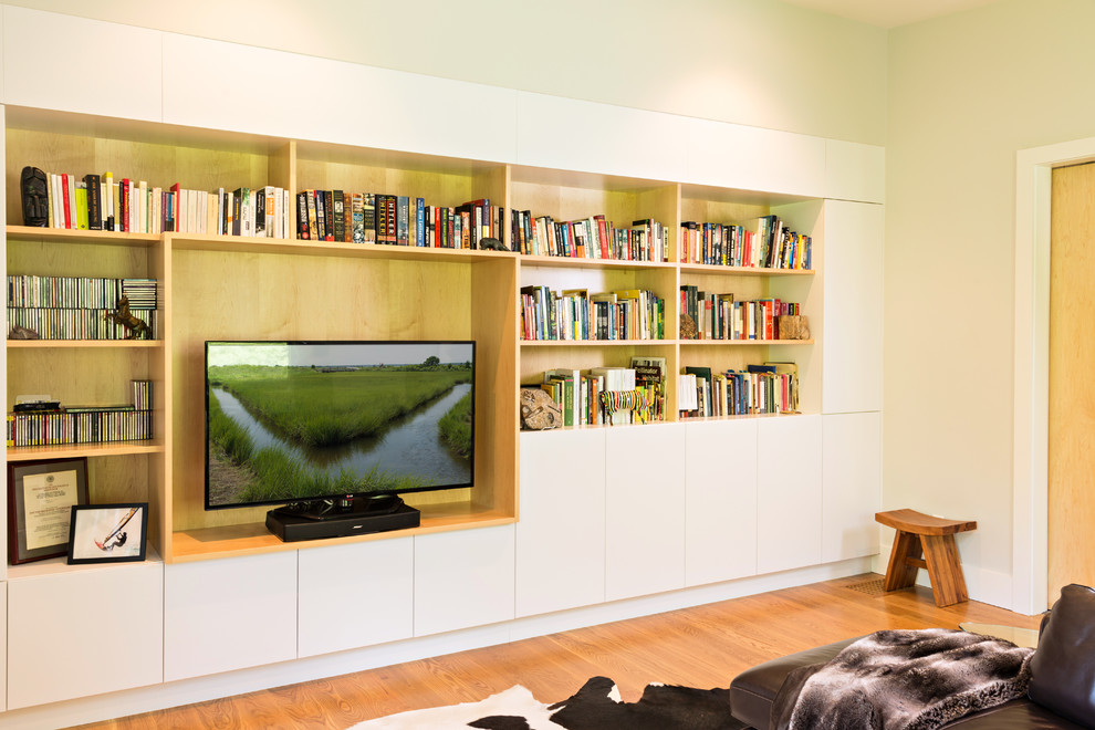 Imagen de sala de estar con biblioteca cerrada minimalista de tamaño medio con paredes beige, suelo de madera en tonos medios, pared multimedia y suelo beige