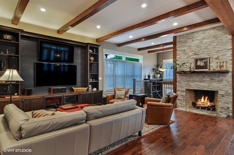 This is an example of a large classic open plan games room in Chicago with grey walls, dark hardwood flooring, a standard fireplace, a stone fireplace surround, a built-in media unit and brown floors.