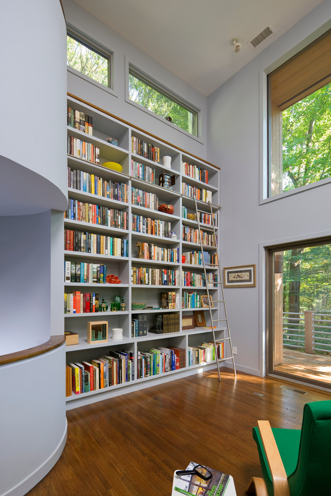 Ispirazione per un soggiorno moderno chiuso con libreria, pareti bianche, pavimento in legno massello medio e nessuna TV