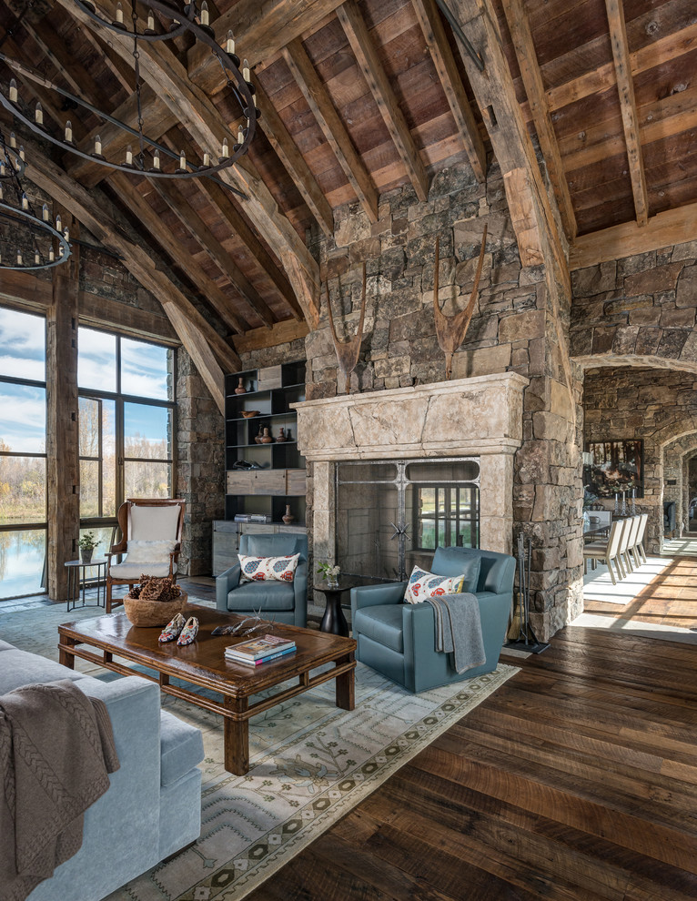 Photo of a large rustic open plan games room in Jackson with a reading nook, dark hardwood flooring, a two-sided fireplace, a stone fireplace surround, no tv and beige walls.
