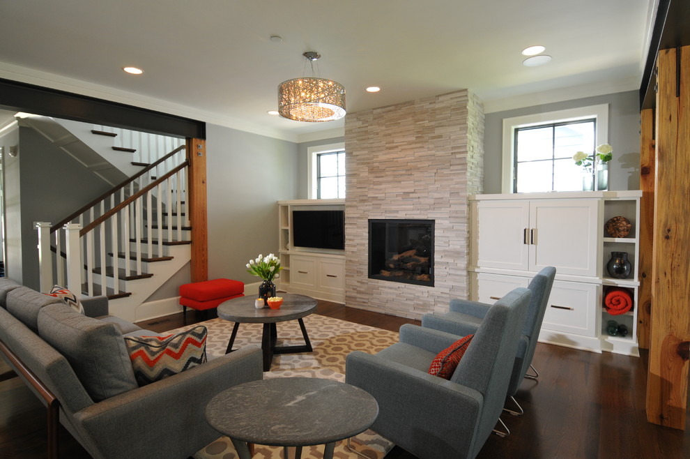 Diseño de sala de estar abierta tradicional renovada de tamaño medio con paredes grises, suelo de madera oscura, marco de chimenea de piedra y pared multimedia