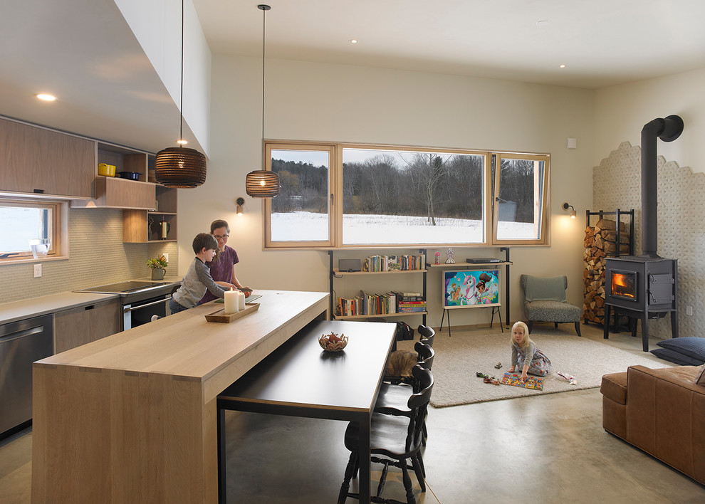 Modelo de sala de estar abierta contemporánea pequeña con paredes beige, suelo de cemento, estufa de leña y marco de chimenea de baldosas y/o azulejos