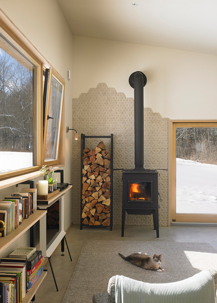 Cette photo montre une petite salle de séjour tendance ouverte avec un mur beige, sol en béton ciré, un poêle à bois et un manteau de cheminée en carrelage.