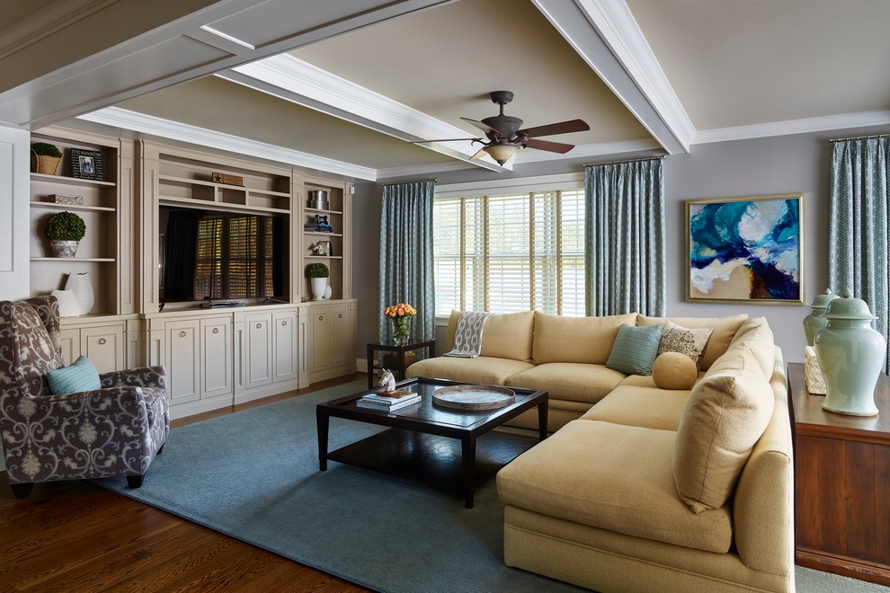 Ejemplo de sala de estar abierta clásica renovada grande sin chimenea con paredes grises, suelo de madera en tonos medios y pared multimedia