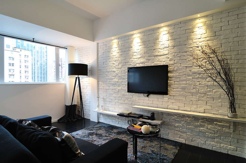 Inredning av ett modernt allrum, med vita väggar, en väggmonterad TV och svart golv