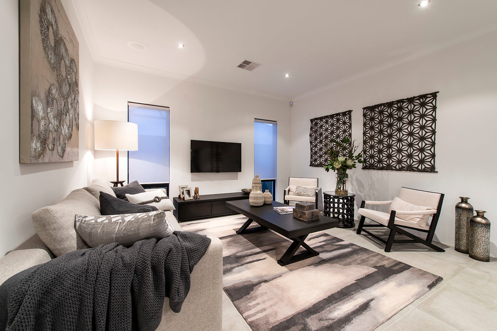 Imagen de sala de estar cerrada actual de tamaño medio sin chimenea con paredes beige y televisor colgado en la pared