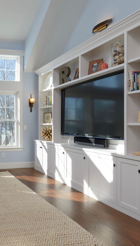 Modelo de sala de estar abierta clásica renovada grande con paredes azules, suelo de madera en tonos medios, pared multimedia, suelo marrón y alfombra