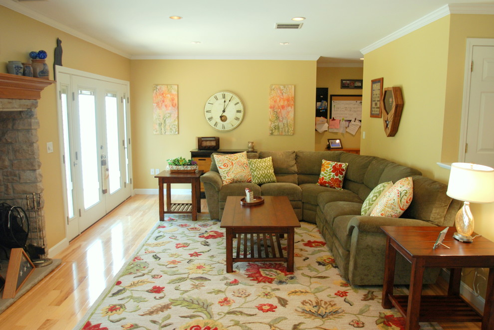 Modelo de sala de estar abierta clásica renovada grande con paredes amarillas, suelo de madera clara y televisor independiente