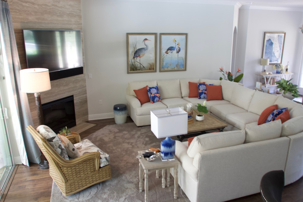 Offenes Maritimes Wohnzimmer mit beiger Wandfarbe, Laminat, Eckkamin, gefliester Kaminumrandung, TV-Wand und braunem Boden in Sonstige