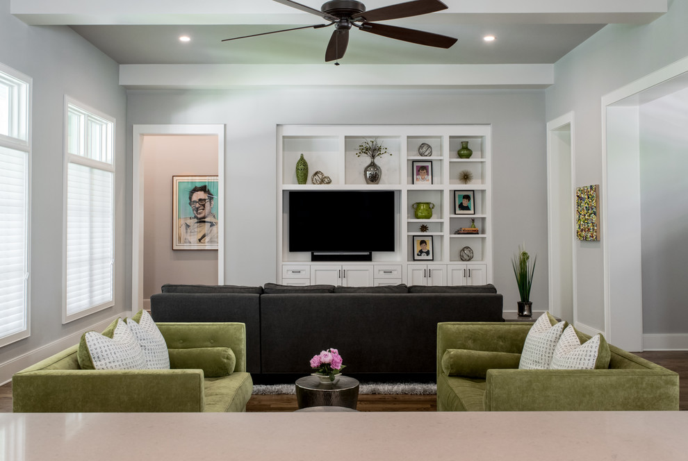 Imagen de sala de estar abierta tradicional renovada grande sin chimenea con paredes grises, suelo de madera en tonos medios y pared multimedia