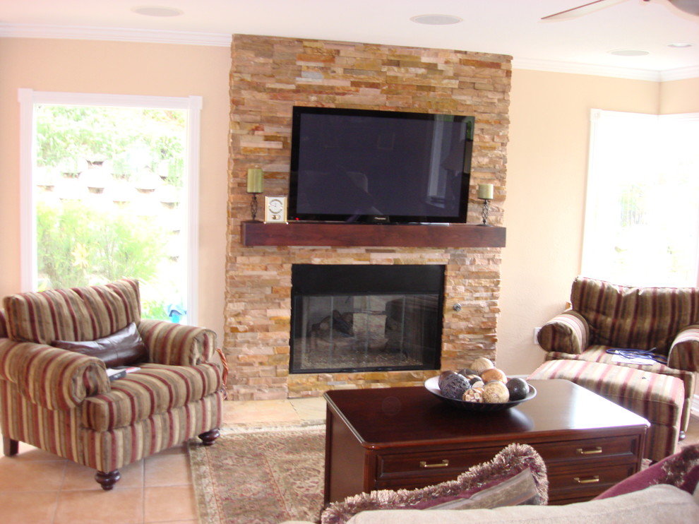 Идея дизайна: открытая гостиная комната среднего размера в стиле неоклассика (современная классика) с бежевыми стенами, полом из керамической плитки, стандартным камином, фасадом камина из камня, телевизором на стене и коричневым полом