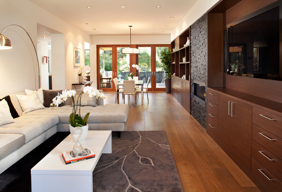 Mittelgroßes, Offenes Modernes Wohnzimmer mit Kaminumrandung aus Stein, weißer Wandfarbe, braunem Holzboden, Kamin, TV-Wand und braunem Boden in San Francisco