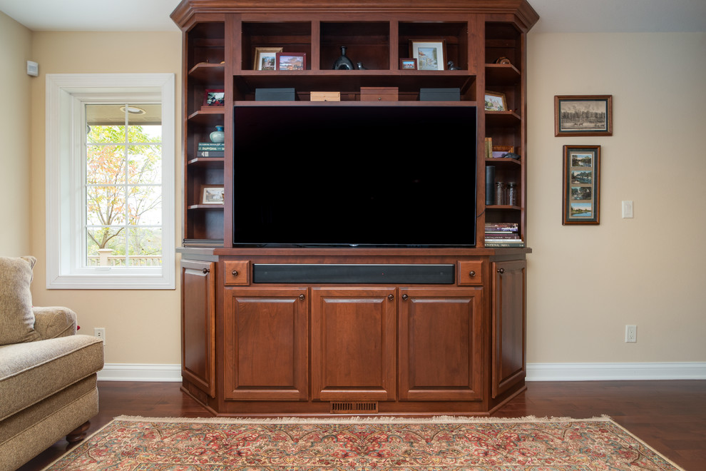 Example of a large classic open concept dark wood floor and brown floor family room design in Milwaukee with beige walls, no fireplace and a media wall