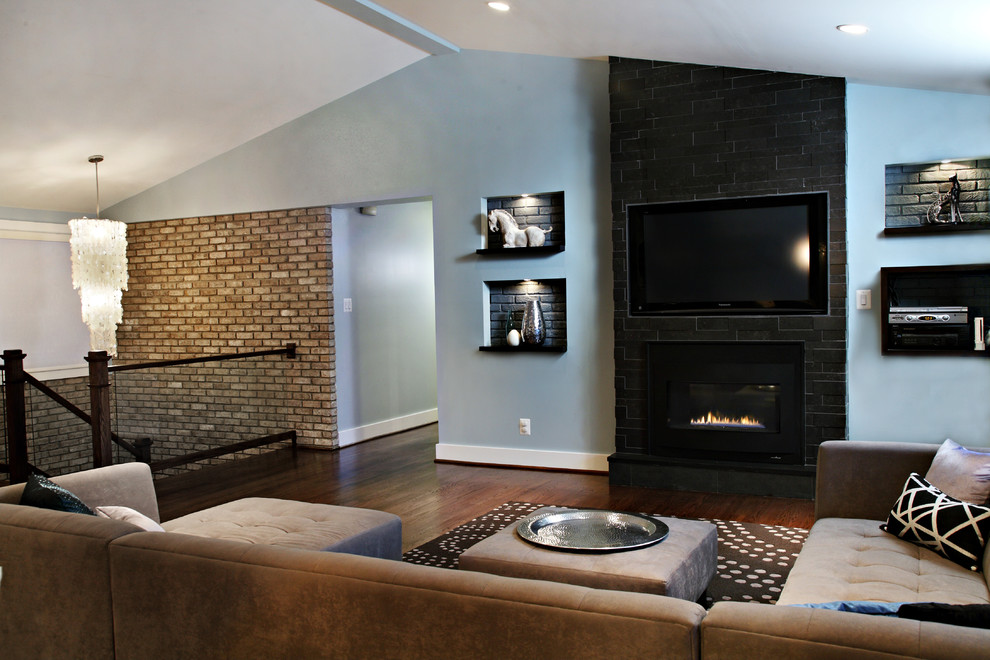 На фото: открытая гостиная комната среднего размера в современном стиле с синими стенами, темным паркетным полом, стандартным камином, фасадом камина из камня и телевизором на стене с