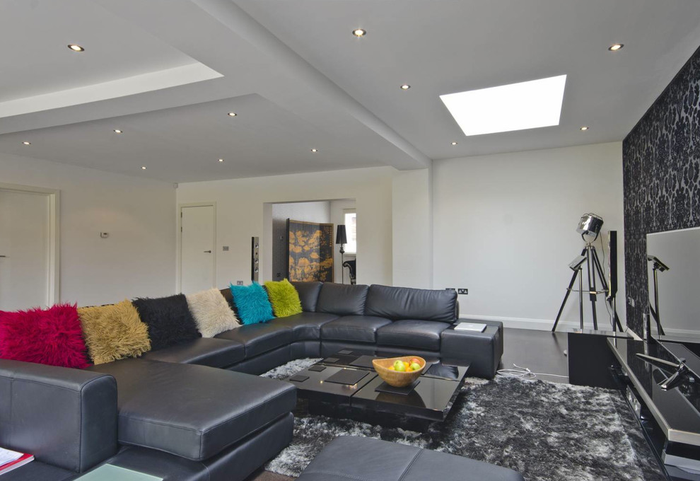 Modelo de sala de estar abierta contemporánea grande sin chimenea con paredes grises, televisor independiente y suelo negro