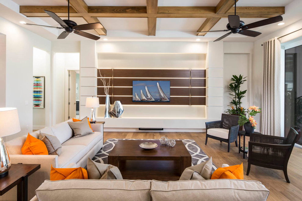 Modelo de sala de estar tradicional renovada grande sin chimenea con paredes blancas, suelo de madera en tonos medios y televisor colgado en la pared