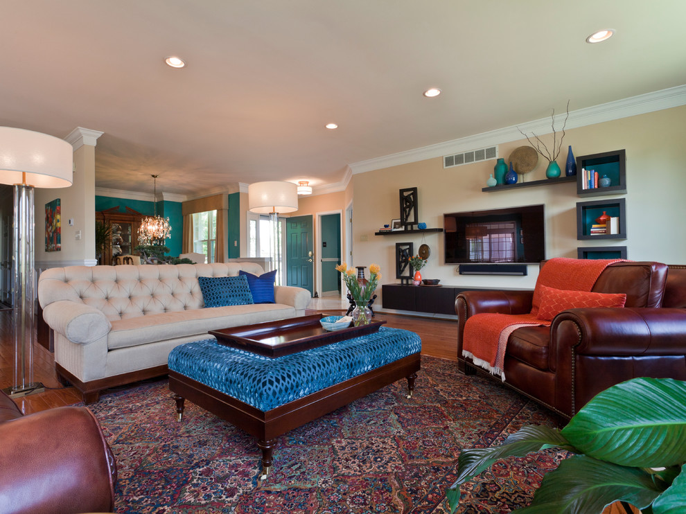Cette image montre une grande salle de séjour traditionnelle ouverte avec un mur bleu, un sol en bois brun, une cheminée standard, un manteau de cheminée en plâtre, un téléviseur fixé au mur et un sol marron.