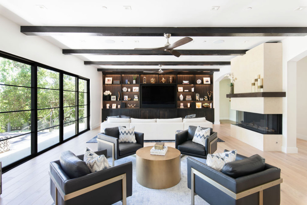 This is an example of a large classic open plan games room in Austin with white walls, light hardwood flooring, a ribbon fireplace, a stone fireplace surround, a built-in media unit and exposed beams.