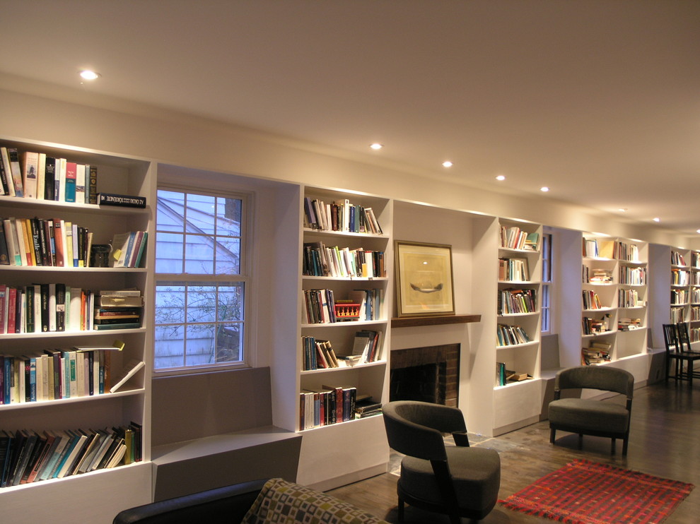 Diseño de sala de estar con biblioteca abierta minimalista con paredes blancas, suelo de madera oscura, todas las chimeneas y marco de chimenea de ladrillo