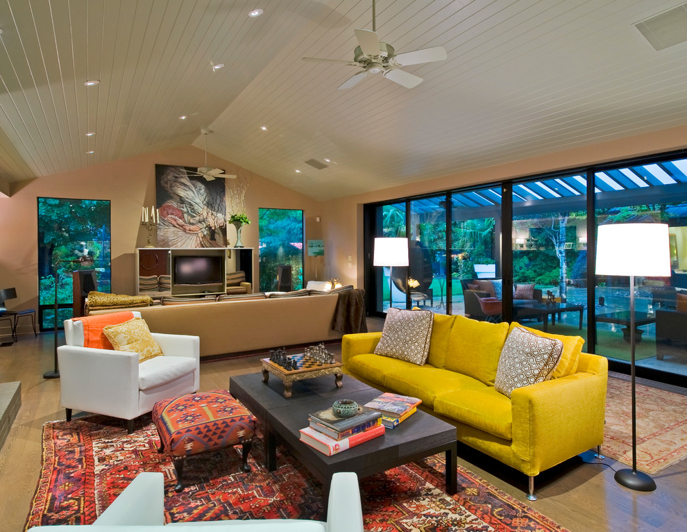 Aménagement d'une salle de séjour contemporaine ouverte avec un mur beige et un sol en bois brun.