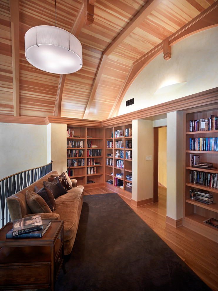 Foto på ett funkis allrum, med ett bibliotek och mellanmörkt trägolv