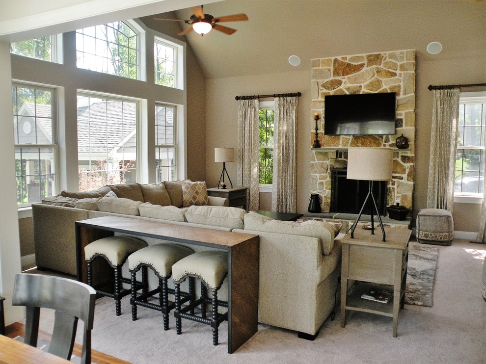 Cette image montre une salle de séjour traditionnelle ouverte avec un mur beige, moquette, une cheminée standard, un manteau de cheminée en pierre et un téléviseur fixé au mur.