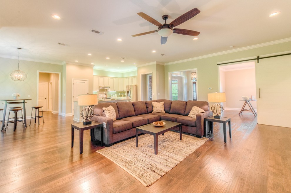 Ejemplo de sala de estar abierta tradicional renovada grande sin chimenea y televisor con paredes beige y suelo de madera en tonos medios