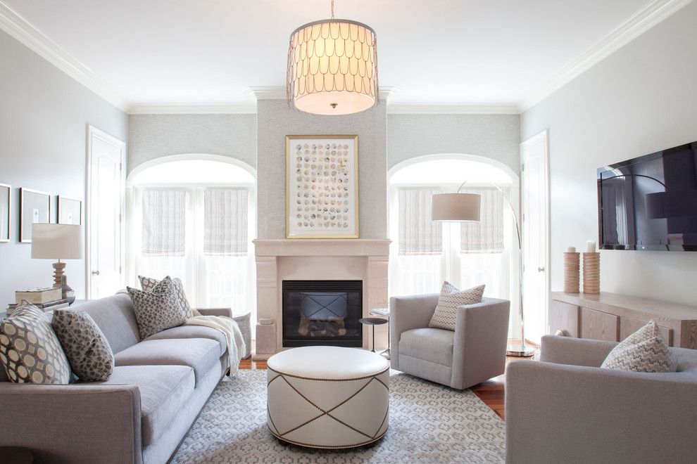 Imagen de sala de estar abierta clásica renovada con paredes grises, suelo de madera en tonos medios, todas las chimeneas, marco de chimenea de piedra, televisor colgado en la pared y alfombra