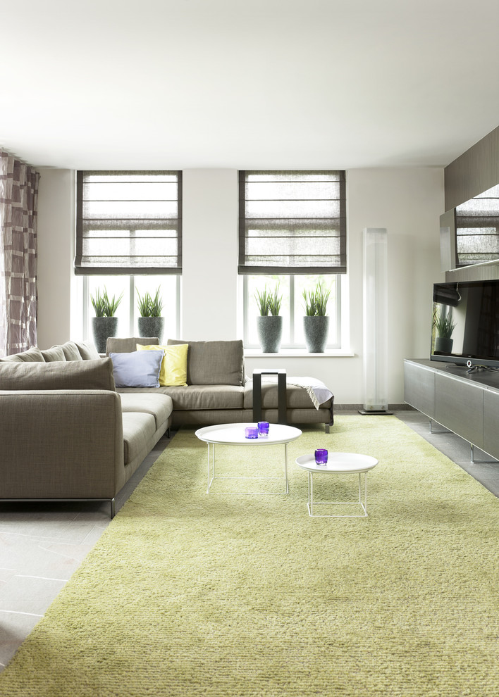 На фото: гостиная комната в стиле модернизм с отдельно стоящим телевизором, серым полом и акцентной стеной с
