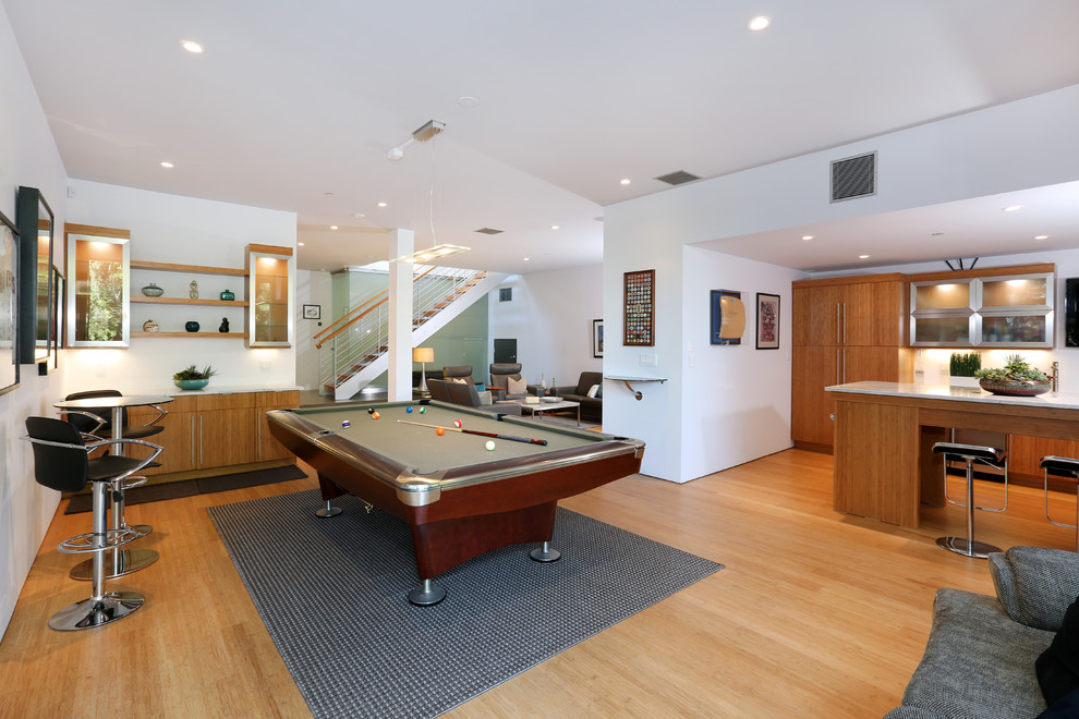 This is an example of a large contemporary open plan games room in Orange County with white walls, bamboo flooring and a wall mounted tv.