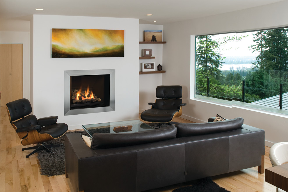 Cette image montre une salle de séjour minimaliste ouverte et de taille moyenne avec un mur blanc, parquet clair, une cheminée standard, un manteau de cheminée en plâtre et un sol beige.