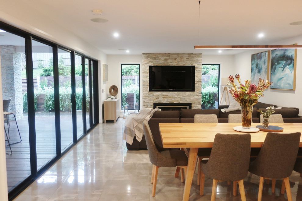 Design ideas for a large contemporary open plan games room in Melbourne with white walls, porcelain flooring, a standard fireplace, a stone fireplace surround, a built-in media unit and grey floors.