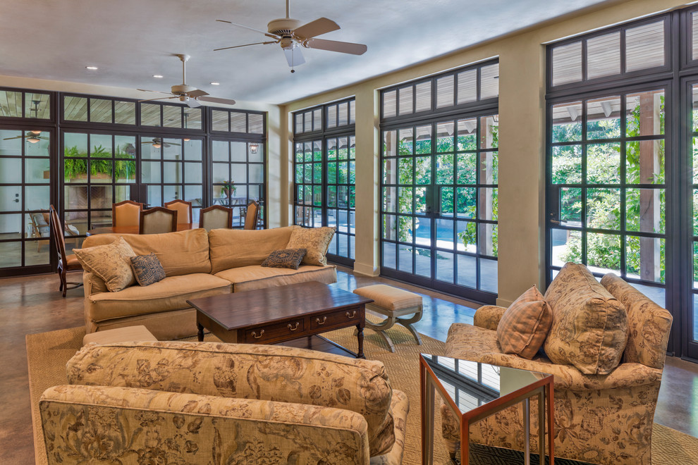 Diseño de sala de estar abierta de estilo americano grande sin chimenea con paredes blancas, suelo de cemento y suelo marrón