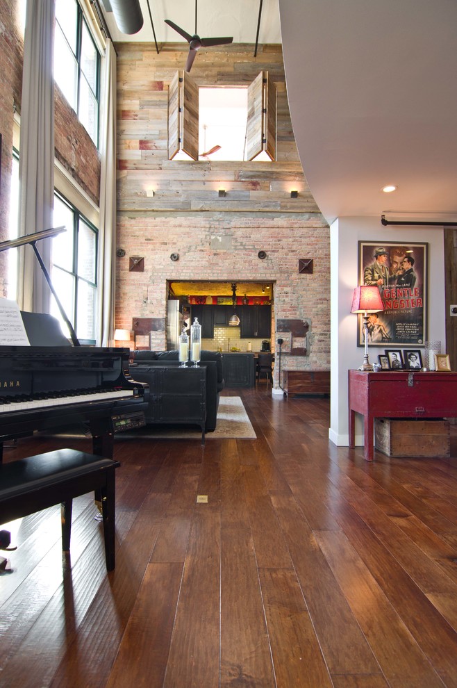 Foto di un soggiorno industriale con pavimento in legno massello medio e TV a parete