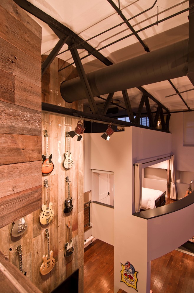 Exempel på ett industriellt allrum på loftet, med vita väggar, mellanmörkt trägolv och en väggmonterad TV