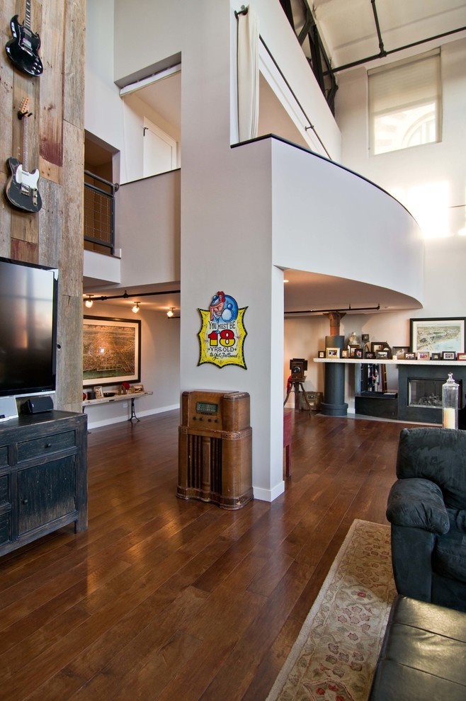 На фото: двухуровневая гостиная комната в стиле лофт с белыми стенами, паркетным полом среднего тона и телевизором на стене