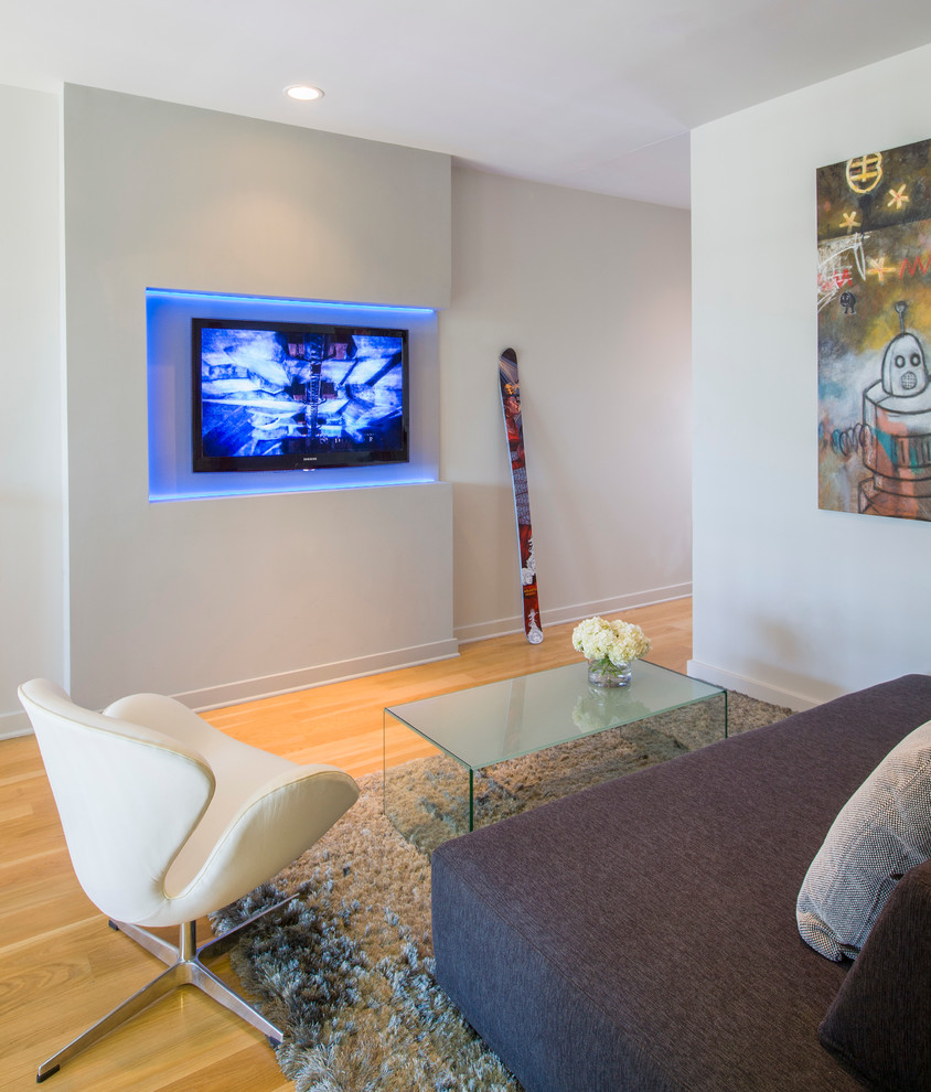 Modelo de sala de estar abierta moderna pequeña con paredes blancas, suelo de madera en tonos medios y televisor colgado en la pared