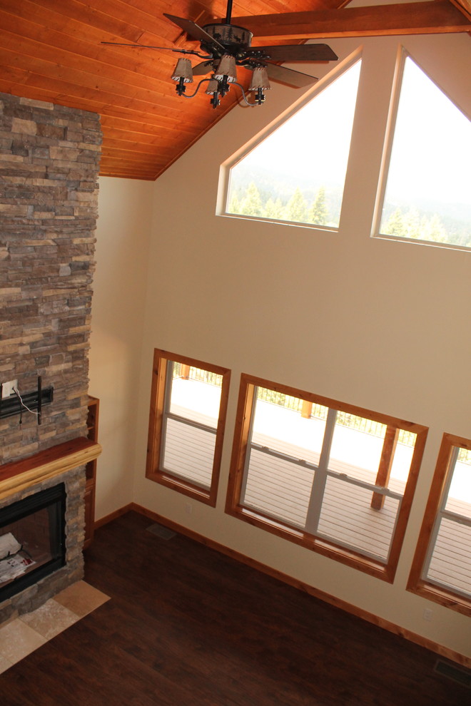 На фото: двухуровневая гостиная комната среднего размера в стиле рустика с бежевыми стенами, полом из ламината и коричневым полом с