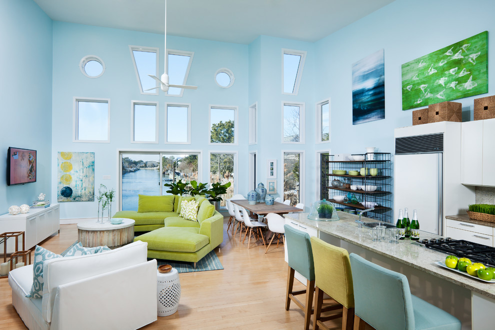На фото: большая двухуровневая гостиная комната в морском стиле с синими стенами, полом из бамбука, угловым камином, фасадом камина из металла, телевизором на стене и бежевым полом