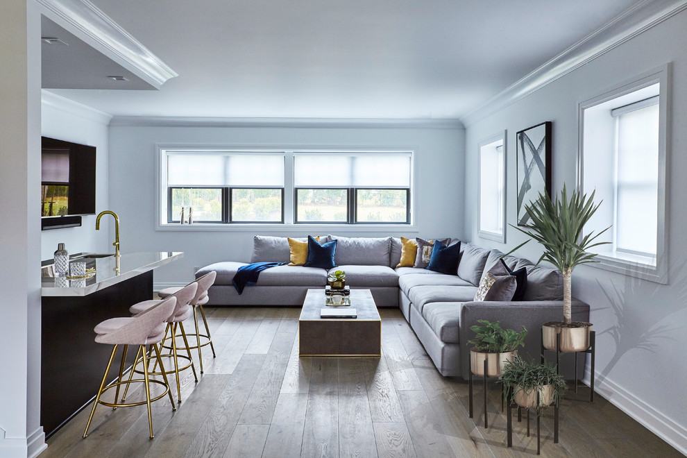 Inspiration for a large contemporary open plan games room in New York with white walls, light hardwood flooring, a wall mounted tv and grey floors.