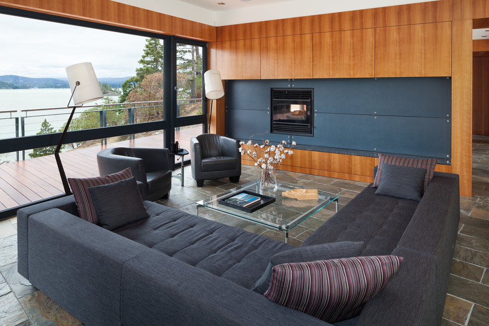 На фото: большая открытая гостиная комната в современном стиле с коричневыми стенами, полом из сланца, стандартным камином и фасадом камина из металла