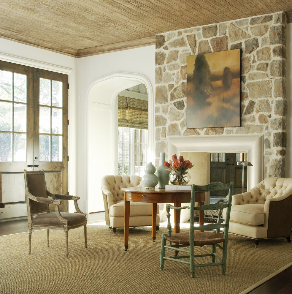 Diseño de sala de estar clásica con paredes blancas, suelo de madera oscura, chimenea de doble cara y marco de chimenea de piedra